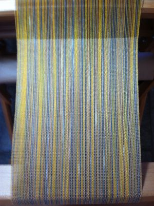 Warp is variegated yarn alternating with solid color yarn.  Weft is skinner solid color; plain weave structure..